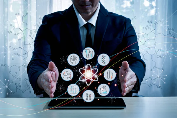 An Asian man wearing a suit Sitting at a desk with a tablet placed And put both hands on the table There is a health icons  placed on the tablet screen. Background and blurred  chemical bond.