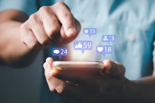 Akıllı telefon yazmayı kullanan bir adam diğerleriyle emoji yoluyla iletişim kurmak ve çevrimiçi mesaj atmak için. Uyarı simgeleri içeren konsept, ileti, e- posta, yorum ve akıllı telefon ekranının üzerindeki yıldız gibi