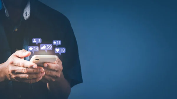 Akıllı telefon yazmayı kullanan bir adam diğerleriyle emoji yoluyla iletişim kurmak ve çevrimiçi mesaj atmak için. Uyarı simgeleri içeren konsept, ileti, e- posta, yorum ve akıllı telefon ekranının üzerindeki yıldız gibi