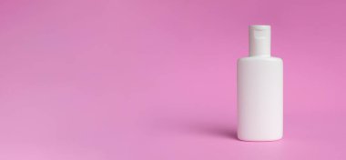 Beyaz losyon şişesi ya da pembe arka planda izole edilmiş krem. Yerdeki gölgeler bulanık