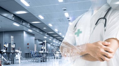 Steteskoplu profesyonel bir doktor klinikte çapraz kollarla ayakta duruyor. Hastanede çalışan genç doktorlar var. Tıp ve sağlık hizmetleri kavramı