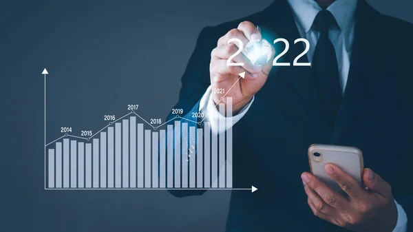 Takım elbiseli bir işadamı cep telefonu tutuyor. Sol elinde 2022 yılının numarasını gösteren bir kalem var. Geçmişi bulanık. Konsept, iş hayatında başarılı olmayı hedefliyor..