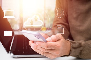 Bir iş adamı modern bir cep telefonu ve bilgisayar arayüzü kullanarak Cloud Computing diyagramı üzerinde çalışır..