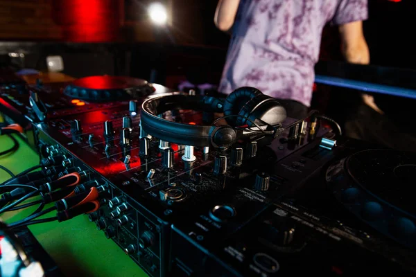 DJ vardiyası bitiyor. Gece kulübünde bir iş. Üzerinde kulaklık bulunan disk jokey konsolunun ya da pikabın fotoğrafını kapat. Arka planda kırmızı ışıklar olan karanlık oda. Karıştırma ekipmanı.