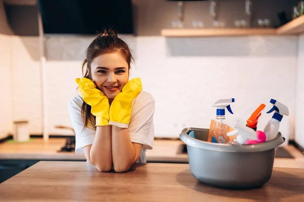 Красивая женщина в защитных желтых перчатках улыбается на кухне во время уборки. — стоковое фото