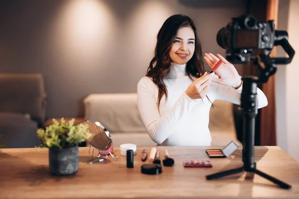 Beauty blogger pretty female filming daily make-up routine tutorial on camera. Influencer young woman live streaming cosmetics product review in home studio. Vlogger job. DIY.