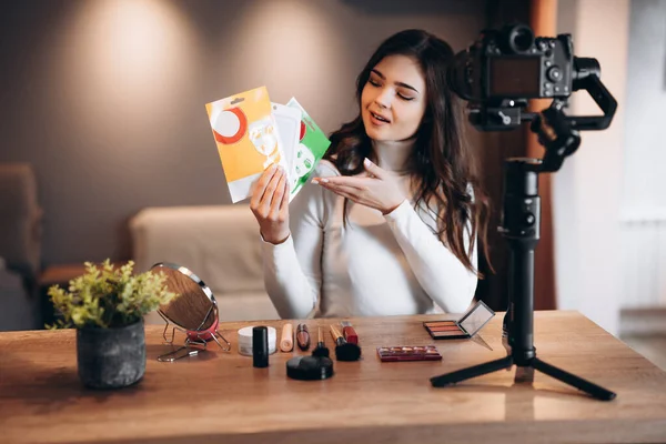 Beauty blogger nice female filming daily make-up routine tutorial on camera. Influencer young woman live streaming cosmetics product review in home studio. Vlogger job. Showing makeup and care