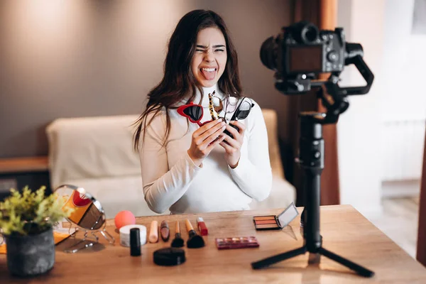 Szépség blogger másoló női forgatás napi smink rutin bemutató kamera. Befolyásos fiatal nő élő streaming kozmetikai termék felülvizsgálat hazai stúdióban. Vlogger munka. Napszemüveg tartása — Stock Fotó