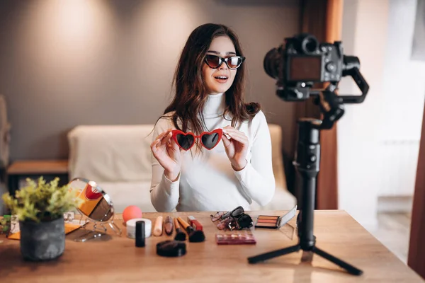 Szépség blogger csinos nő napszemüvegben forgatás napi make-up rutin bemutató kamera. Befolyásos fiatal nő élő streaming kozmetikai termék felülvizsgálat hazai stúdióban. Vlogger munka. Tartás — Stock Fotó