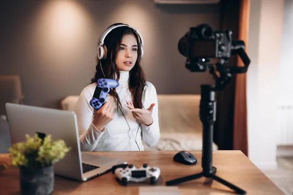 Bella blogger donna sorpresa in cuffia è in streaming in diretta parlando di videogiochi. Influencer giovane donna live streaming tenere joystick. — Foto Stock