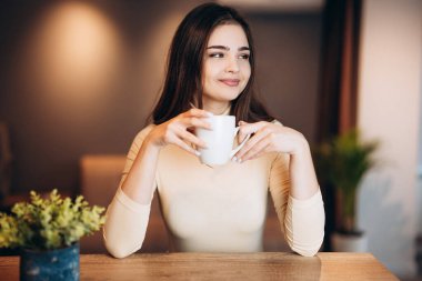 Şirin genç kız çalışırken evde çay kahvesi içiyor. Serbest çalışan bir kadın. Öğrenci kız.