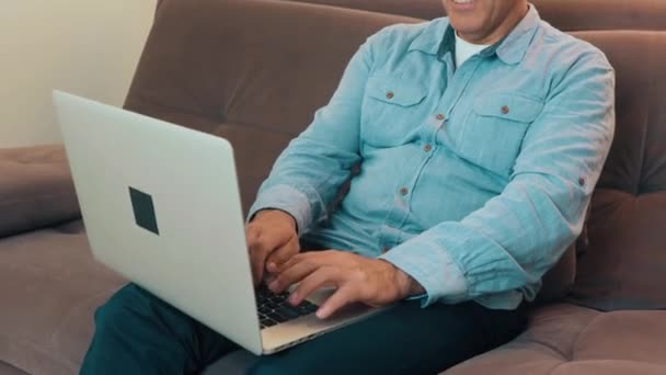 Middle aged man using modern laptop to read news or reply to emails. Blue shirt and jeans. Modern technology concept. — Stock Video