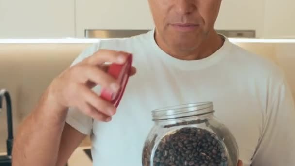 Middle aged man holds a jar of coffee beans. Jar of coffee beans. Start your morning with a cup of hot tasty espresso. He wants to make himself delicious coffee for breakfast. — Stock Video