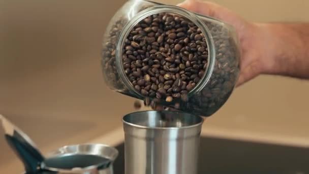 Κοντινό πλάνο των κόκκων καφέ σε ένα δοχείο χύνεται σε ένα μύλο καφέ. Σπιτικός καφές το πρωί — Αρχείο Βίντεο
