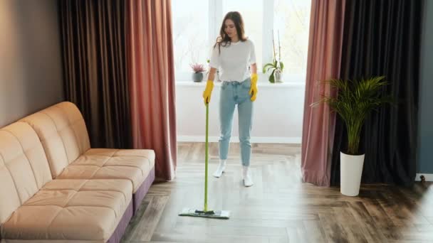 Une jeune femme nettoie à la maison. Brunette modèle féminin lave le sol dans le salon. — Video