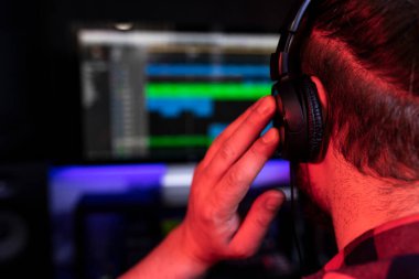 Beyaz genç DJ, müzik stüdyosunda şarkı mikseri ve mikrofon kullanarak yeni bir parça kaydediyor.