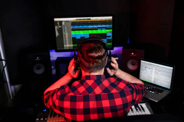 Hipster dj ragazzo con i capelli lunghi sta ascoltando la sua nuova canzone in stereo che ha appena registrato in studio — Foto Stock