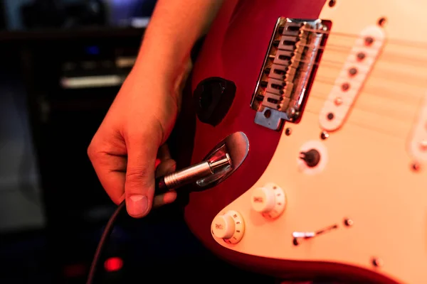 Close up man sta controllando la sua chitarra prima di suonare. L'idea di strumenti musicali fotografici in studio stereo — Foto Stock