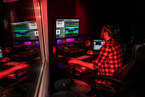 Jovem produtor com barba está trabalhando no mixer com áudio e faixa no estúdio de gravação. — Fotografia de Stock