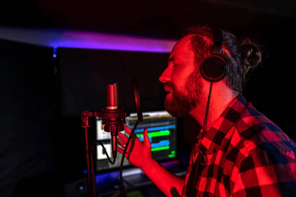 Hombre en los auriculares está sintiendo en el micrófono en la radio transmitir su nueva canción —  Fotos de Stock