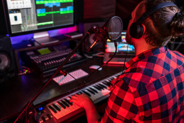 White young man is singing and recording a new track in the stereo studio workplace using song mixer and microphone on broadcast