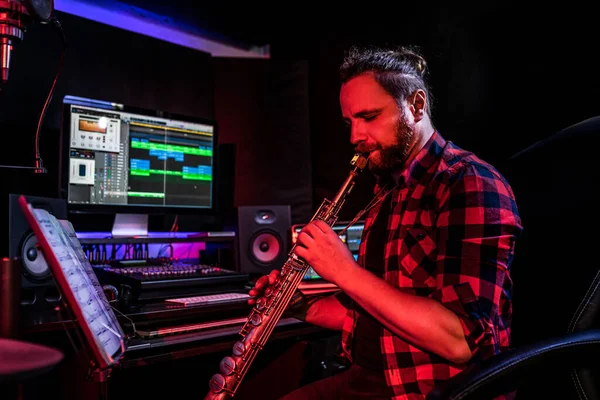 Hipster withe young man with beard is playing on musical instrument in the studio to record his brand-new song