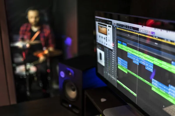 Bilgisayardaki ses programı DJ, söz yazarı, yapımcı için genç adam davul çalarken müzik stüdyosunda yeni fikirler yaratmak için.
