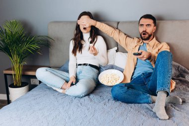 Omg, ne oldu? Tatlı çiftin karantina altında boş zaman filmleri var. Beklenmedik bir gerilim filmi, gözlerini patlamış mısır kutusuyla kapatıyor. Evin içinde kanepede oturuyor. Hoş bir çift.