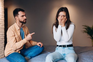 İlişki sorunları ve engeller, çatışma ve insanların kavramı - evde tartışan mutsuz bir çift. Sorunları olan genç bir çift kanepede otururken neredeyse kavga ediyor..