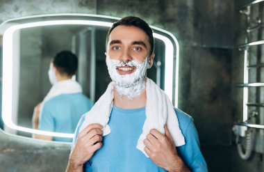 Yakışıklıymış. Boynunda havlu ve yüzünde köpükle kameraya bakarken gülümsüyormuş..