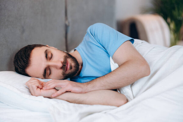 Вид красивого спокойного мужчины с бородой, лежащего на подушке и спящего по утрам.