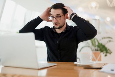 Neler oluyor? Gözlüklü akıllı adam dizüstü bilgisayarına bakıyor ve kafasını ellerinden tutuyor. Programda hata. Erkek programcı kodda ne kadar çok hata olduğuna şaşırır..
