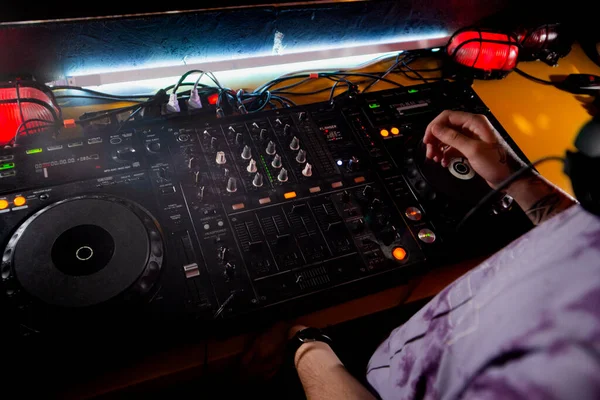 DJ suona dal vivo e mixa musica sulla console del giradischi sul palco del night club. Disco Jokey Mani su una stazione di mixer audio alla festa del club. Pannello controller mixer DJ per riprodurre musica e feste. — Foto Stock