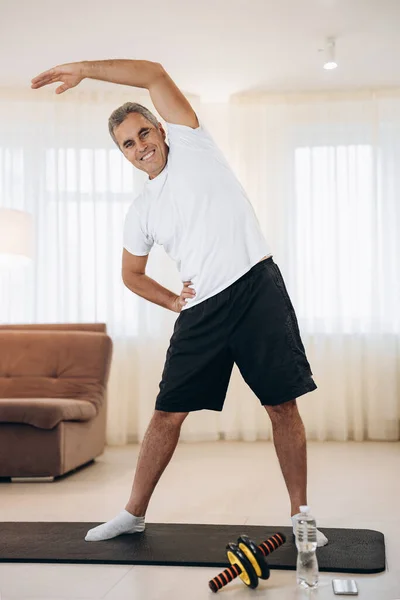 Önce kollarını açıp gülümseyen ve kameraya bakan neşeli son sınıf öğrencisi ısınsın. Yoga minderinde sabah antrenmanı. Güçlü adam vücudun kıvrımlarını yapıyor..