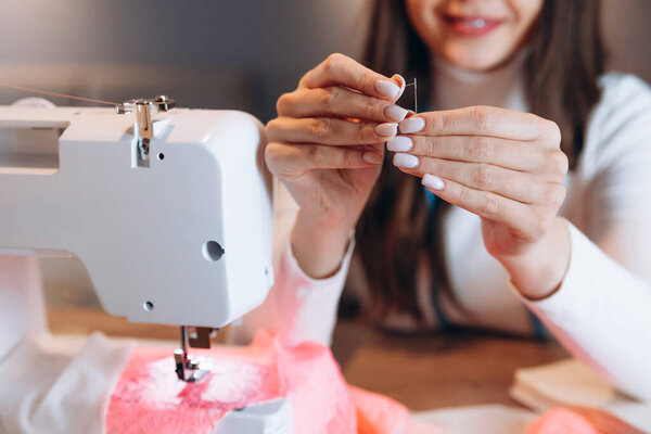 Fingers hands of the seamstress is using a needle close-up. Creating online clothing design courses.
