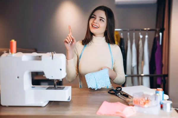 Mujer modista joven cose ropa en la máquina de coser. Soñar y crear costurera en el taller. Creación de cursos de diseño de ropa en línea. — Foto de Stock