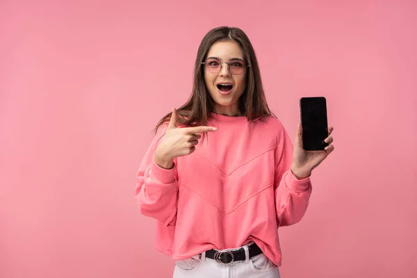 Fénykép vonzó hölgy szemüvegben tartja okostelefon, olvas vagy blogot ír. Visel alkalmi rózsaszín póló fehér nadrág elszigetelt rózsaszín szín háttér. — Stock Fotó