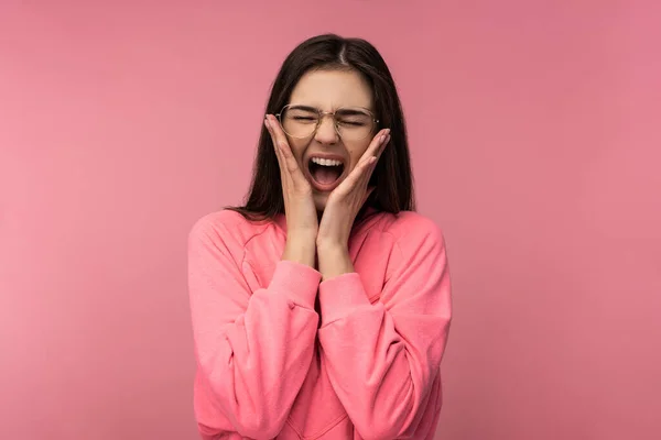 Фото привлекательной молодой женщины в очках, кричащей. Носит случайные розовые футболки изолированный розовый цвет фона — стоковое фото