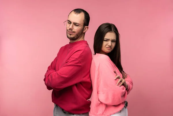 Photo of attractive couple stands back to back and looks resentful and desperate, isolated over pink background — Stock Photo, Image