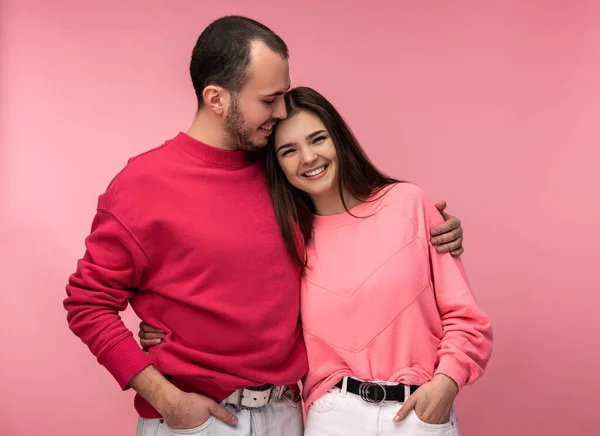 Tatlı çiftin birbirlerine sarılıp gülümsedikleri bir fotoğraf. Erkek ve dişi aşıklar, pembe arka planda soyutlanmışlar.