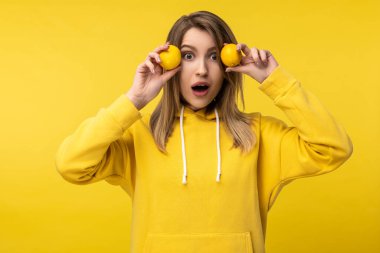 Çekici bir bayanın limonlu pozu. Sıradan sarı kapüşonlu, izole sarı arka plan giyiyor.