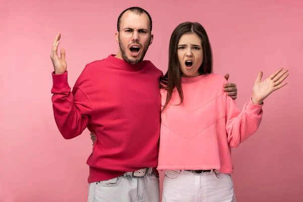 Photo of attractive man wih beard in red clothing and woman in pink are dreadly sorehead, isolated over pink background — Stock Photo, Image
