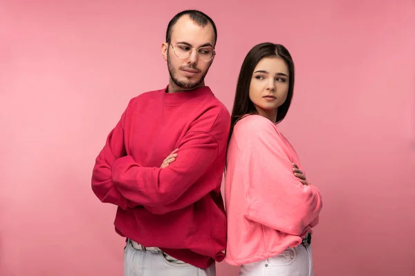 Photo of attractive man wih beard in red clothing and woman in pink stand and pose for camera glare on each other, isolated over pink background — Stock Photo, Image