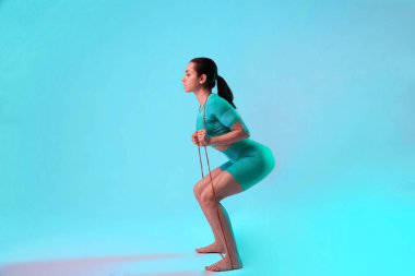 Genç, formda ve beyaz tenli, direniş bandı olan bir kadın. Formda sporcu kadın pozu. Yaz için mükemmel bir vücut. Güzellik, tatil köyü, spor konsepti.