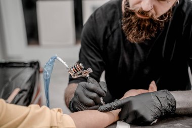 Dövme makinesini kapat. Dövme yaptırıyorum. Profesyonel bir dövmeci tarafından elinde resim oluşturulan bir adam.