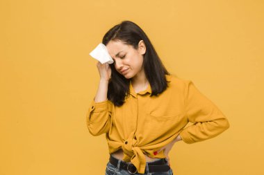 Hasta kadın fotoğrafının baş ağrısı var. Sarı gömlek giyiyor, izole edilmiş sarı arkaplan