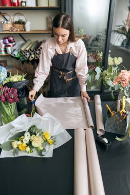 Çiçekçide Kraft 'ın çiçekçisinden önce elinde dekoratif çiçeklerle çiçek yapan kadın..