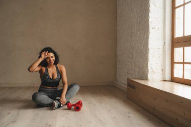 Kadın, sağlık kulübünde dambıllarla antrenmandan sonra dinleniyor. Sportif, çekici bir kadın spor yapıyor. Sağlıklı yaşam tarzı