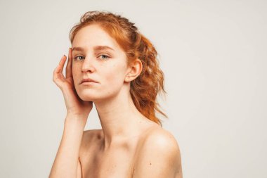 Yakından bakınca doğal kızıl saçlı, çilli çekici bir kadın görüyorum. Beyaz arka planda izole edilmiş. Doğal güzellik ve sağlık