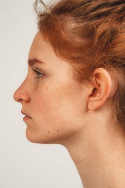 Profilde yüzünü kapat doğal kızıl saçlı, çilli hoş bir kadın. Beyaz arka planda izole edilmiş. Doğal güzellik ve sağlık